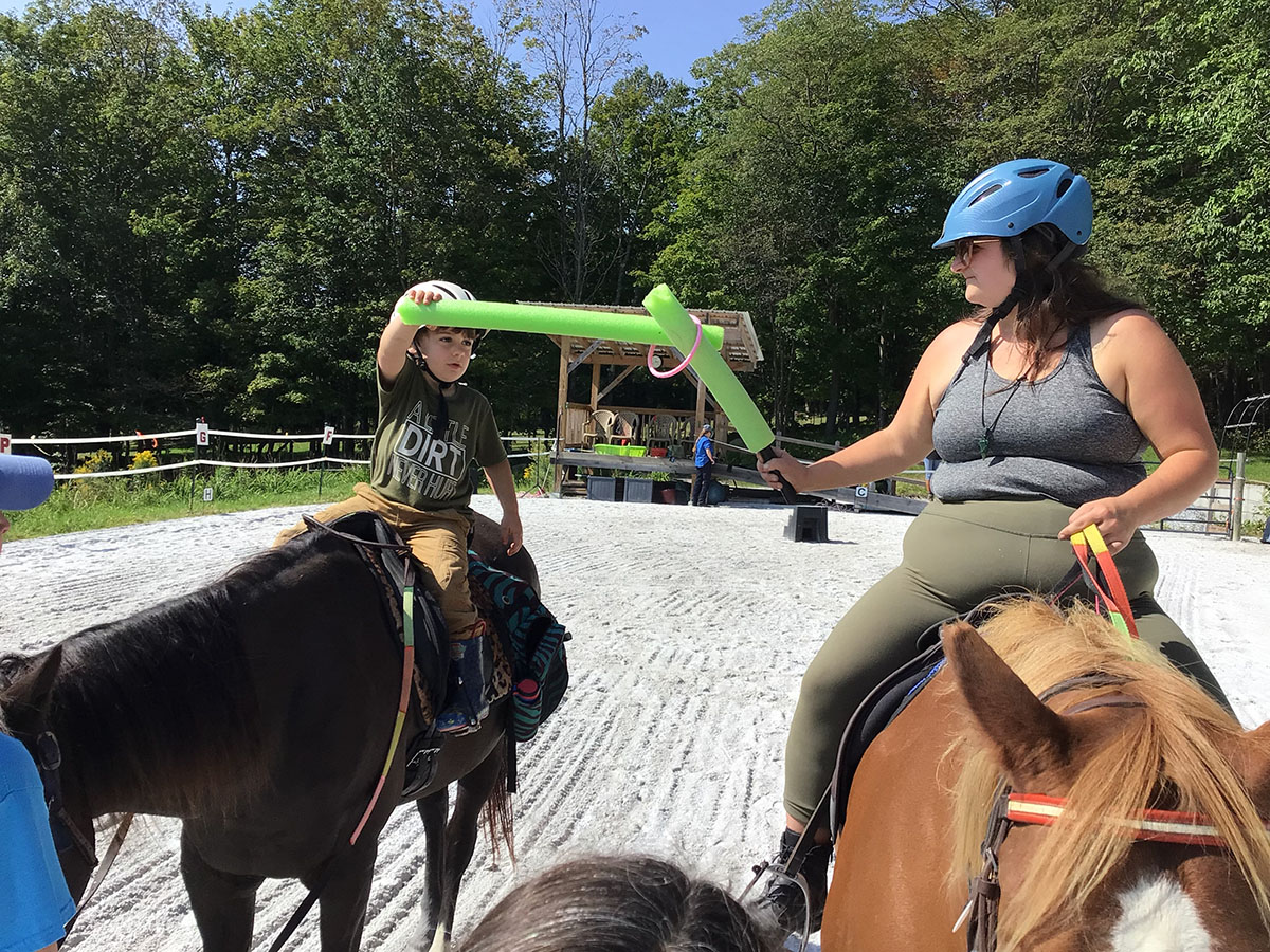 A woman and a boy on horses with a green object.