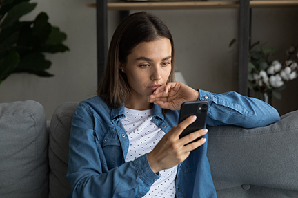 A woman sitting on a couch looking at her phone.