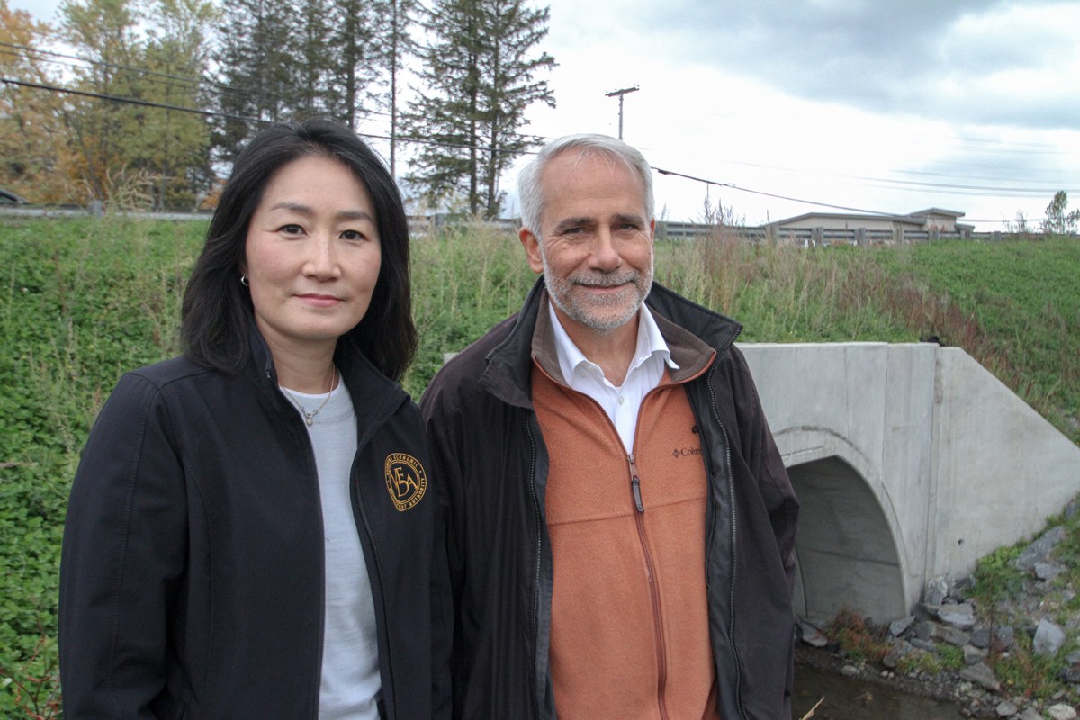 A man and woman standing in front of a bridge.