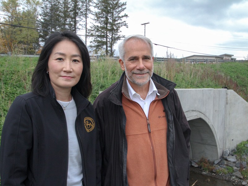 A man and woman standing in front of a bridge.