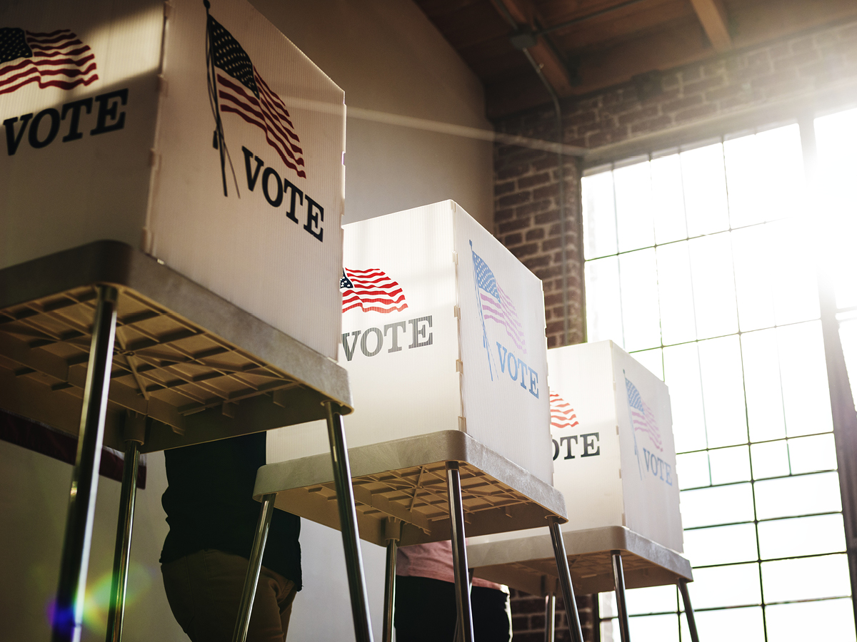 A group of people standing in front of voting boxes.