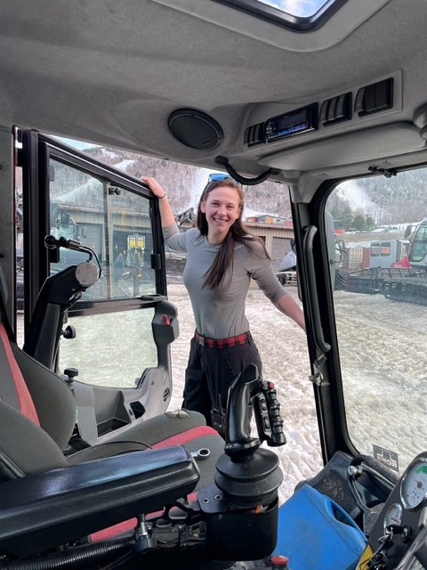 A woman in a tractor smiling in the driver's seat.