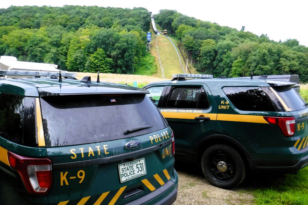 Two police cars parked next to a ski slope.