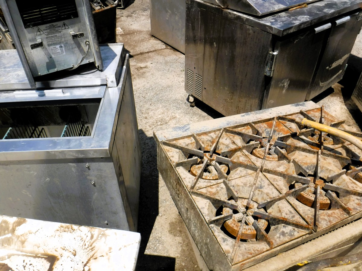 A silver stove in a dirty kitchen.
