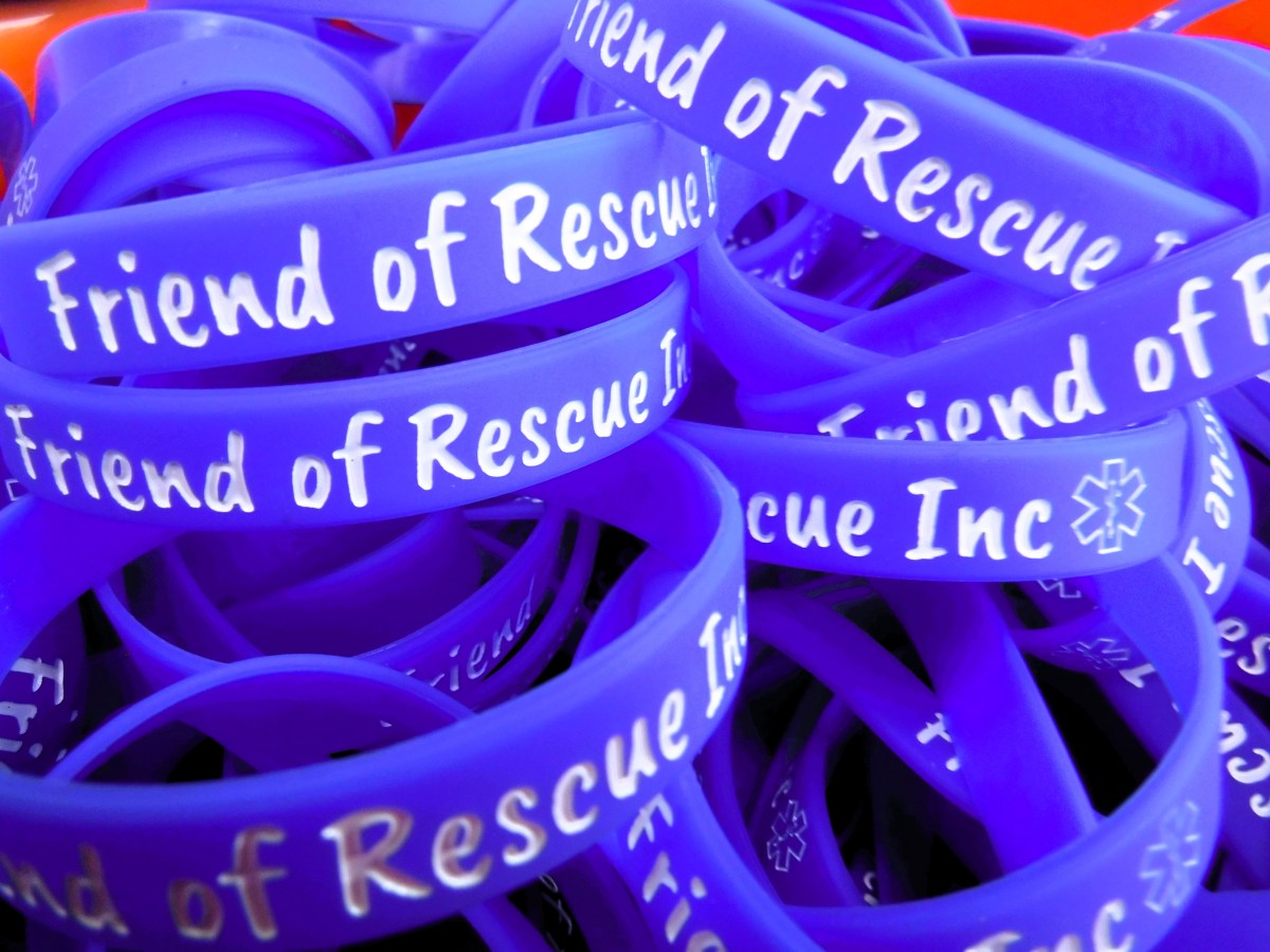 A stack of blue bracelets that say friend of rescue inc.