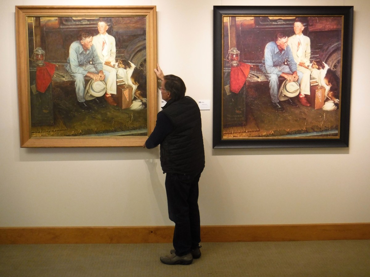A man looking at two paintings in a museum.