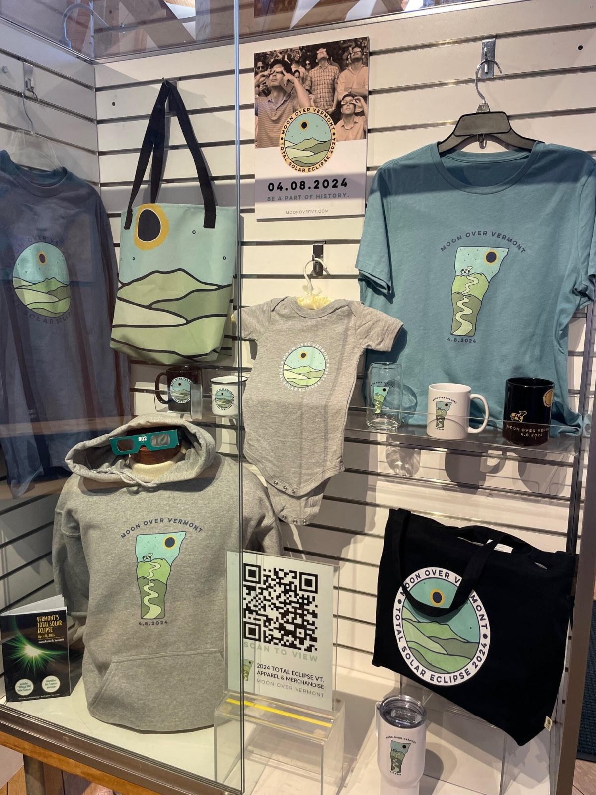 A wall of T-shirts, onesies, sweatshirts and tote bags.