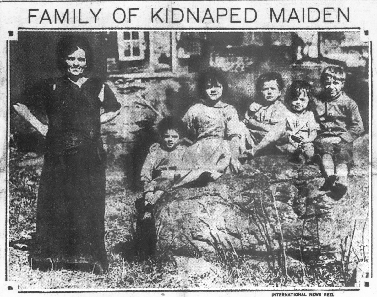 A historical black and white photo depicting a woman and four children, with the caption "family of kidnapped maiden" displayed below.