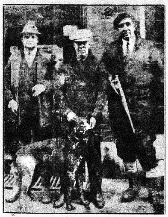 Three individuals in vintage attire with a dog, standing in front of a textured background.