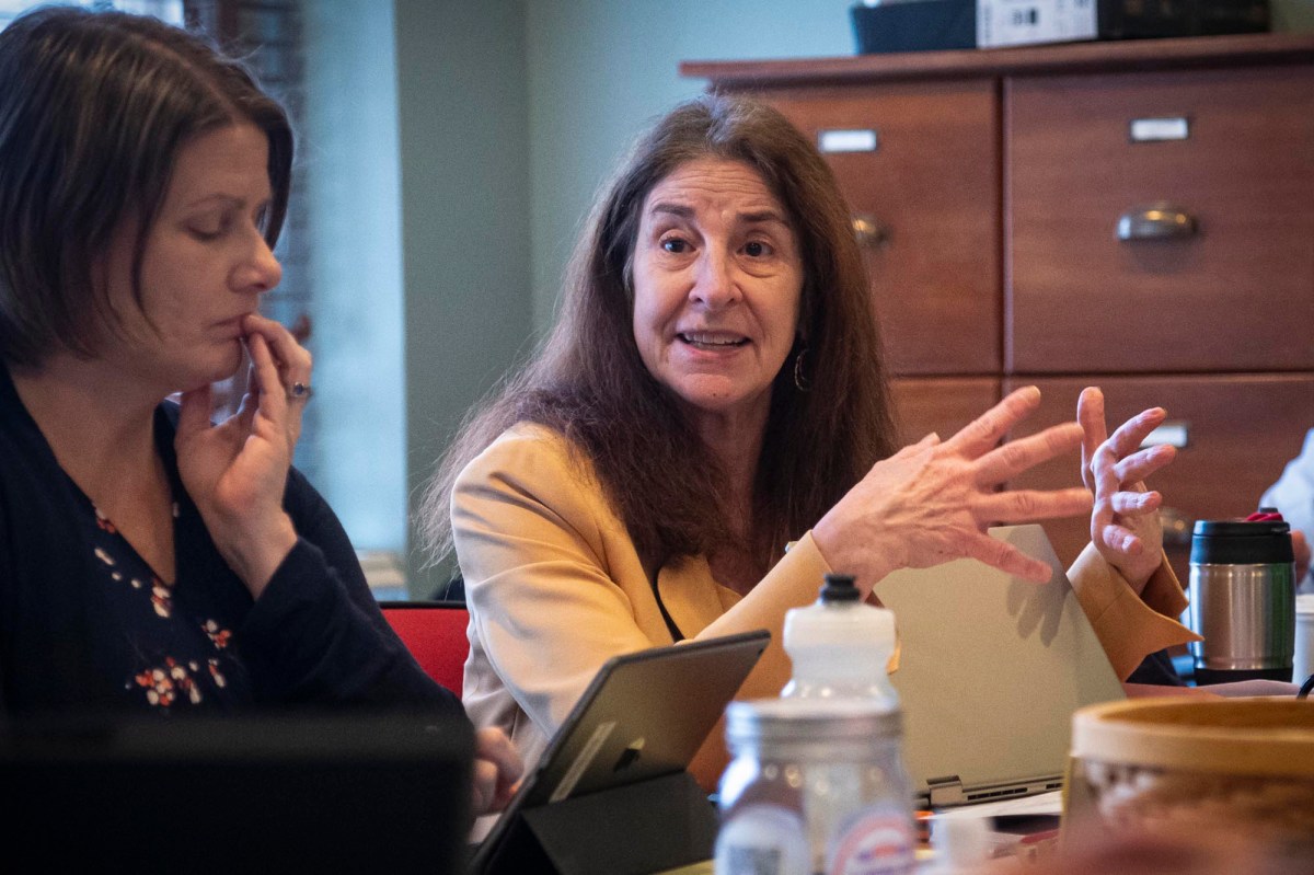 Two women sitting at a table talking to each other.