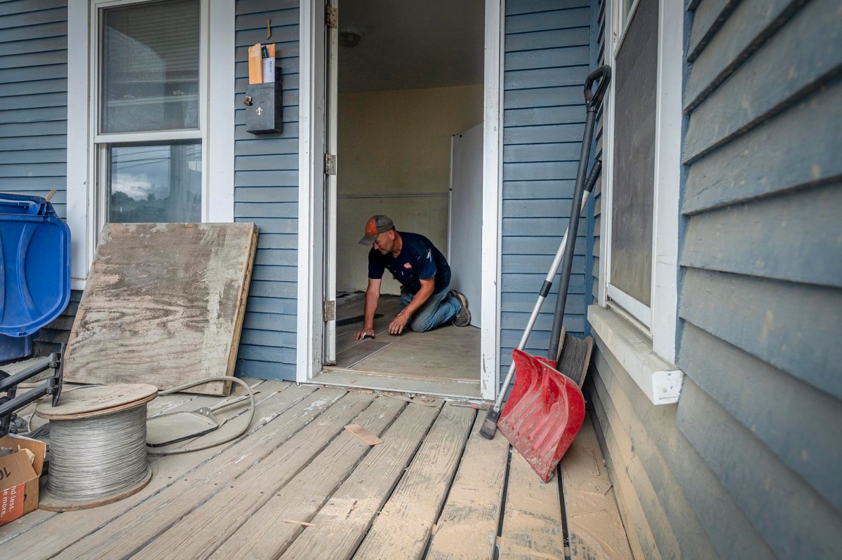 A man standing on a porch with a shovel.