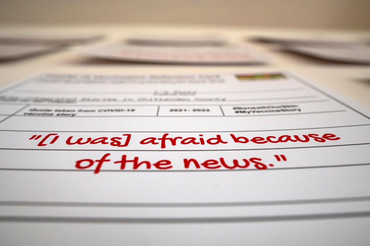 Close-up of a printed document with the phrase "i was afraid because of the news" written in red, with pencils and blurred papers in the background.