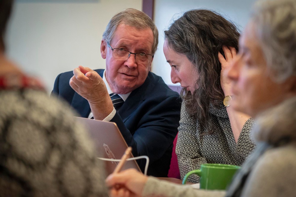 A group of people sitting around a table with a laptop.