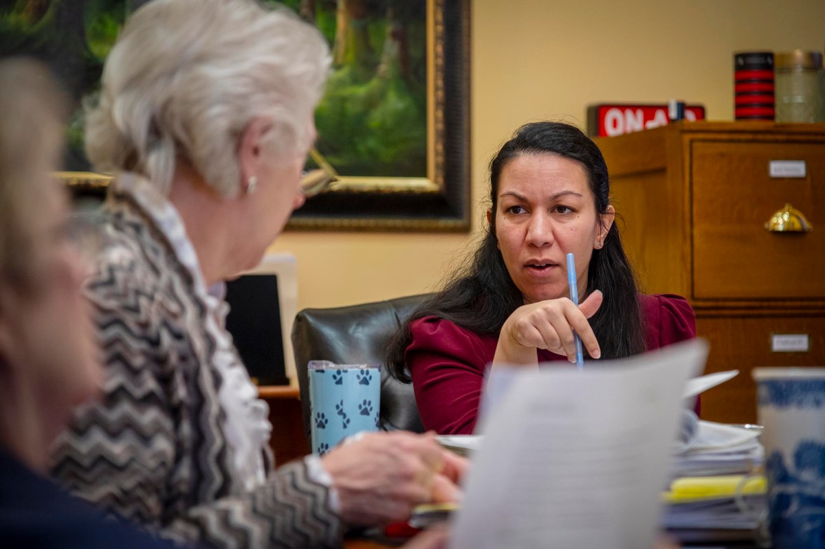 A woman sits at a table with papers in front of her.