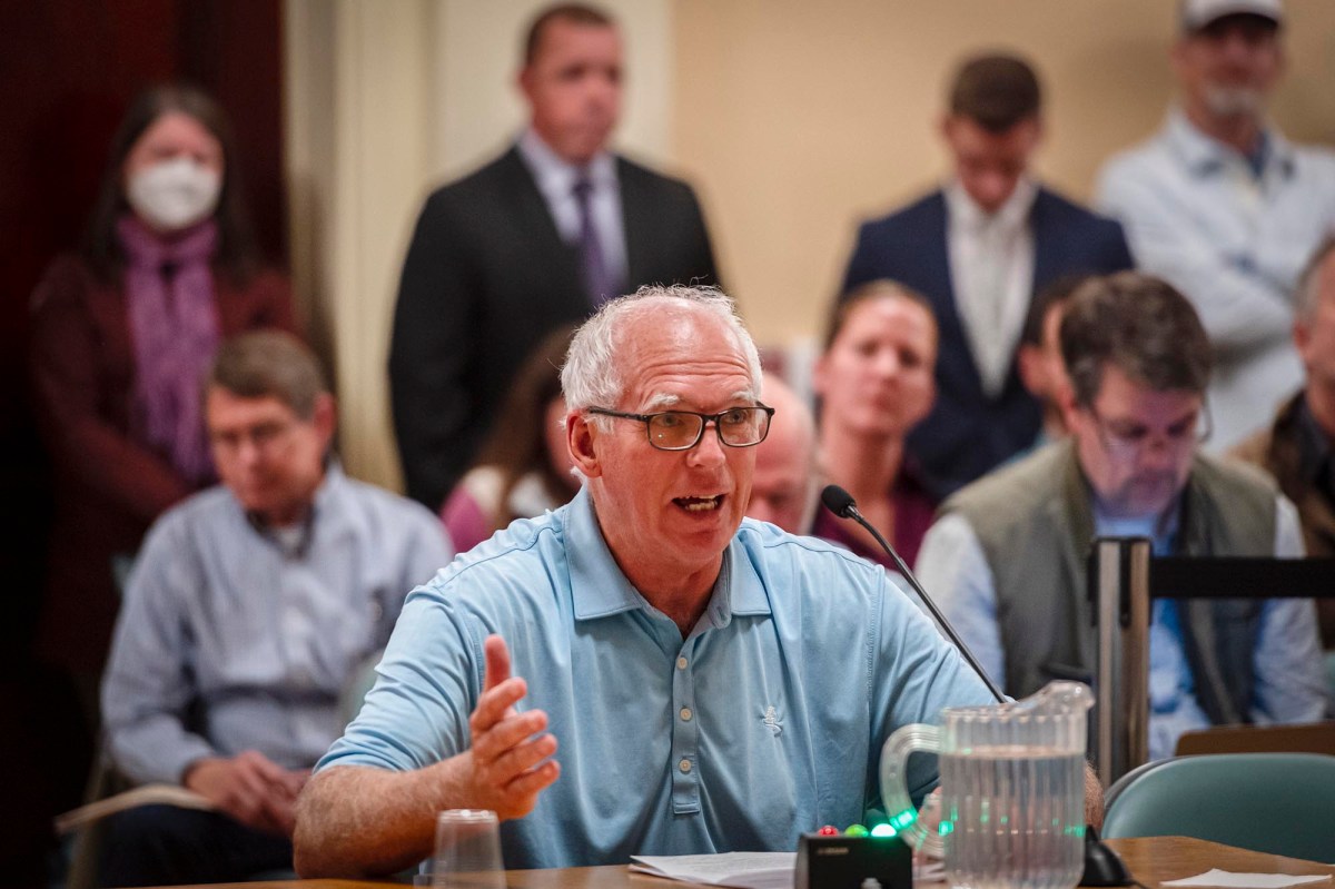 A man sitting at a table in front of a group of people.