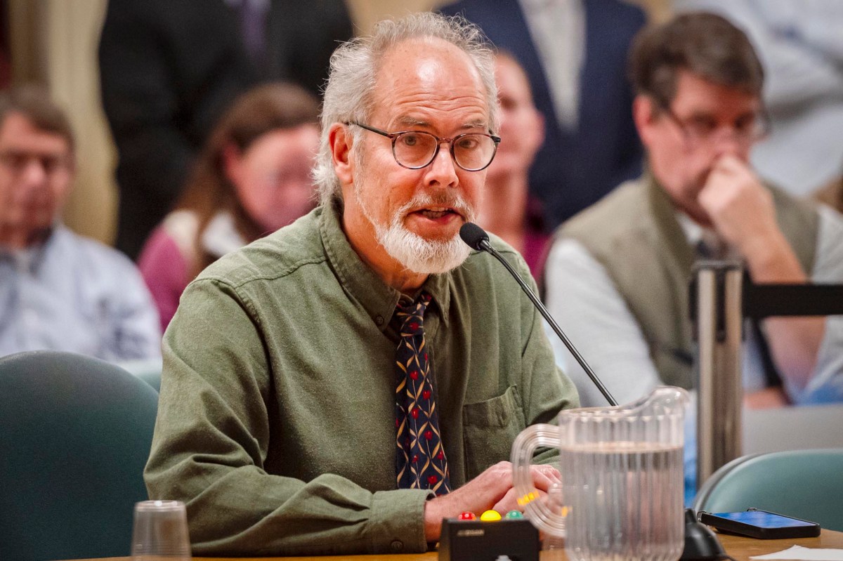 A man sitting at a table in front of a group of people.