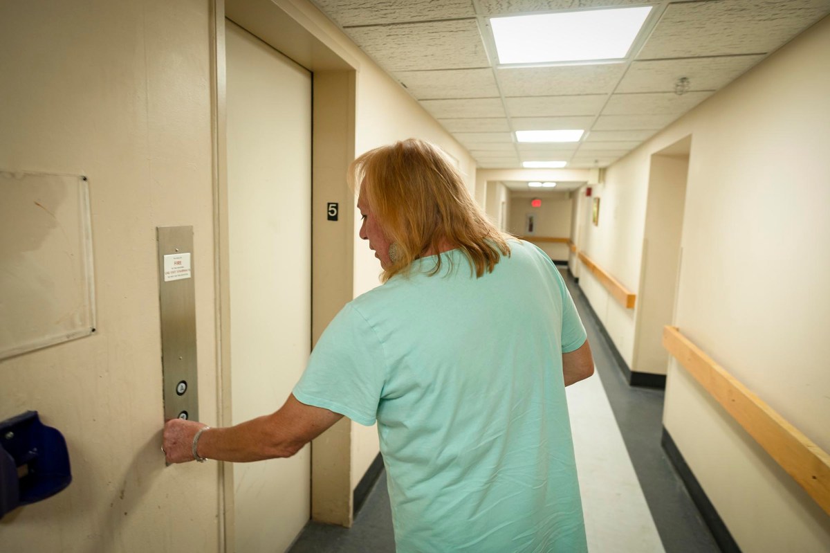 A man in a blue shirt opening a door in a hallway.