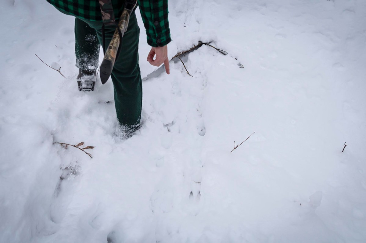A person walking through the snow with a muzzleloader.