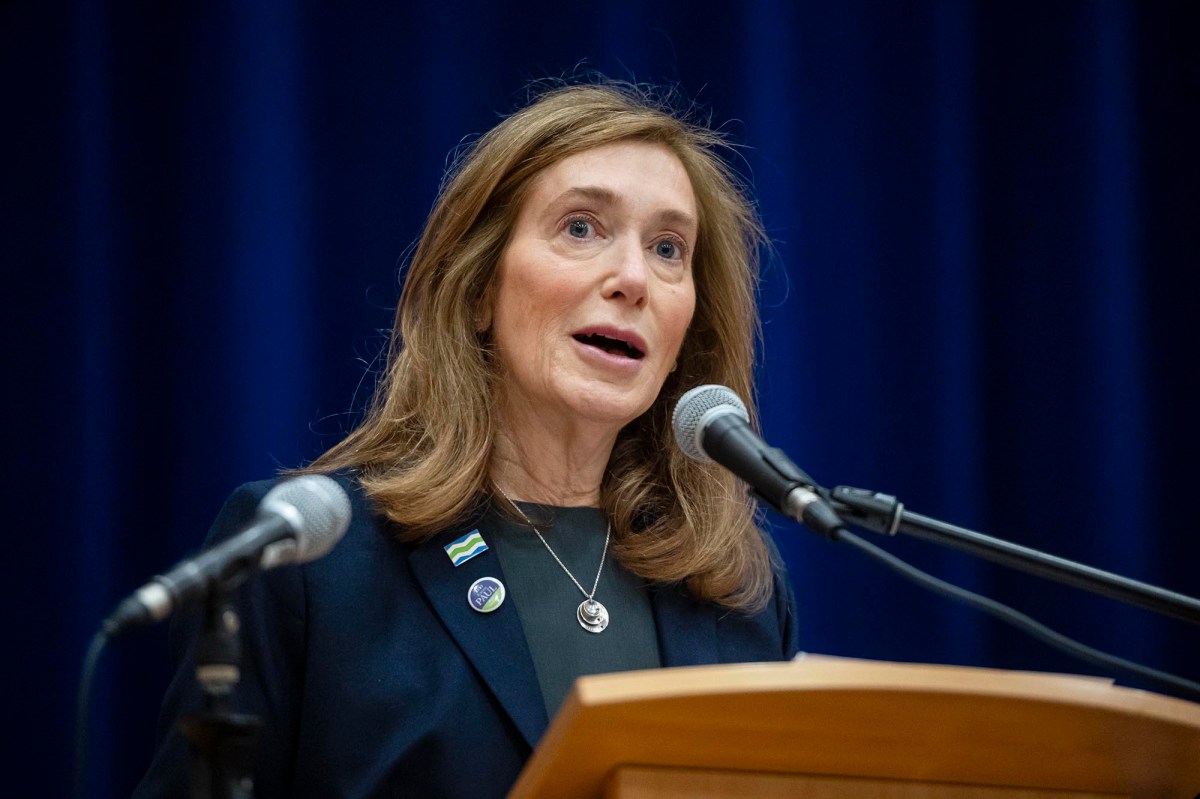 A woman speaking into a microphone at a podium.