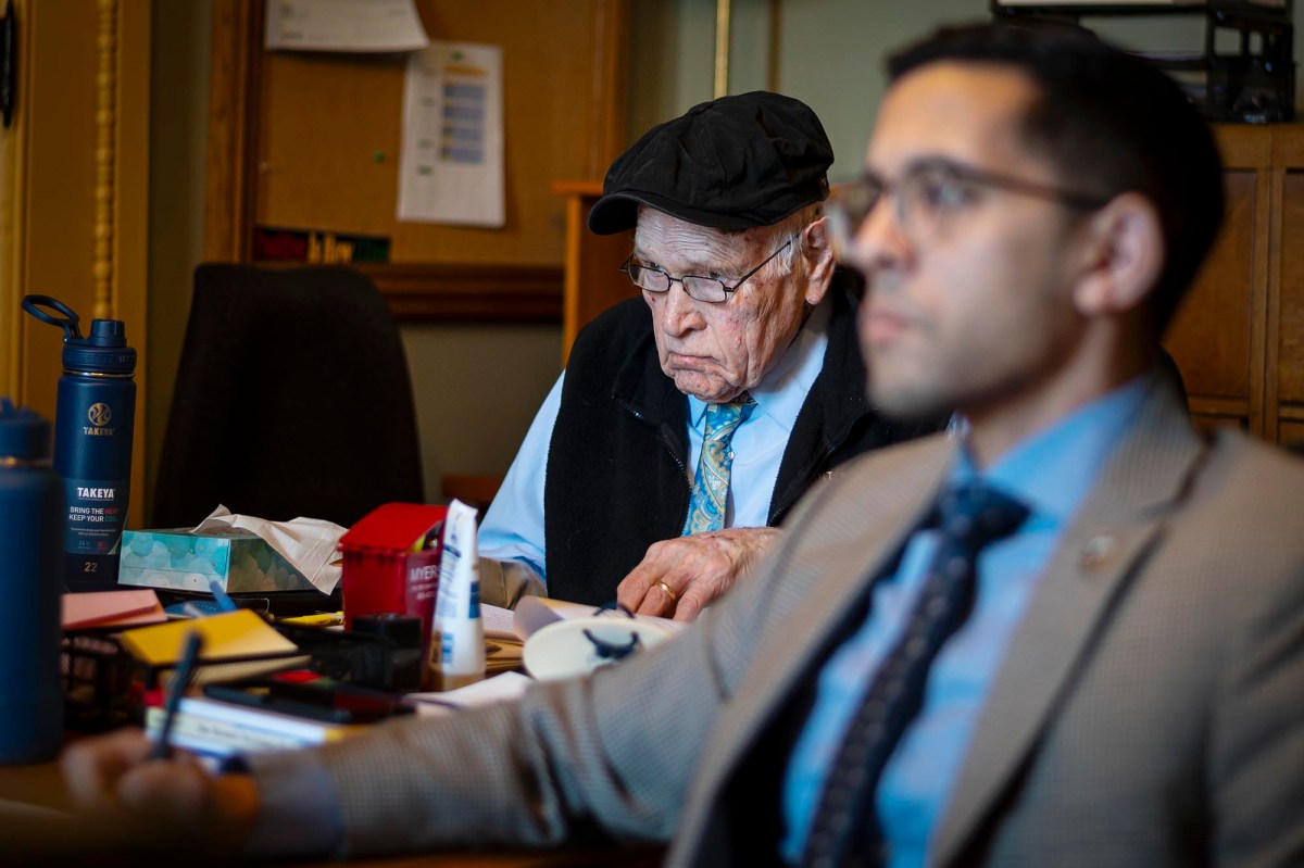 A man in a suit and tie sits at a desk.