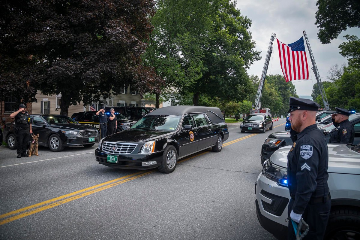 a police car with an american flag on it is driving down the street.