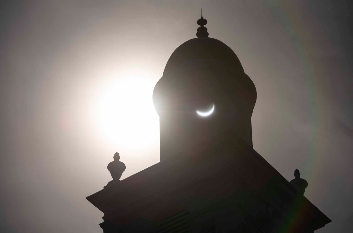 Silhouette of a building's dome against the backdrop of a solar eclipse.
