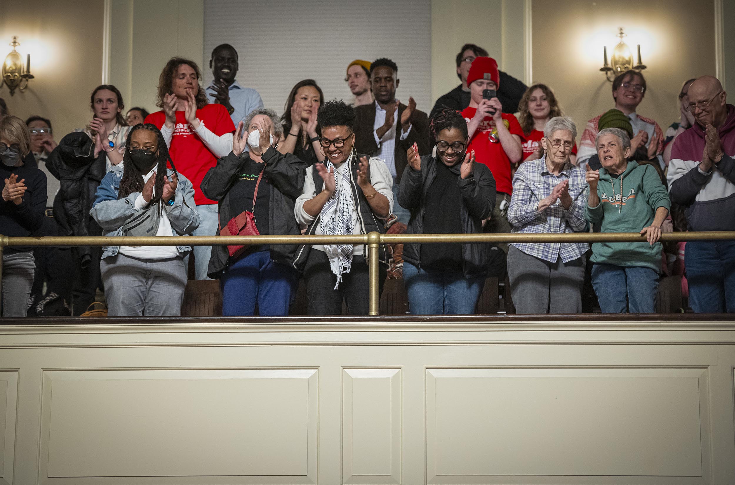 Audience members applauding enthusiastically from a balcony.