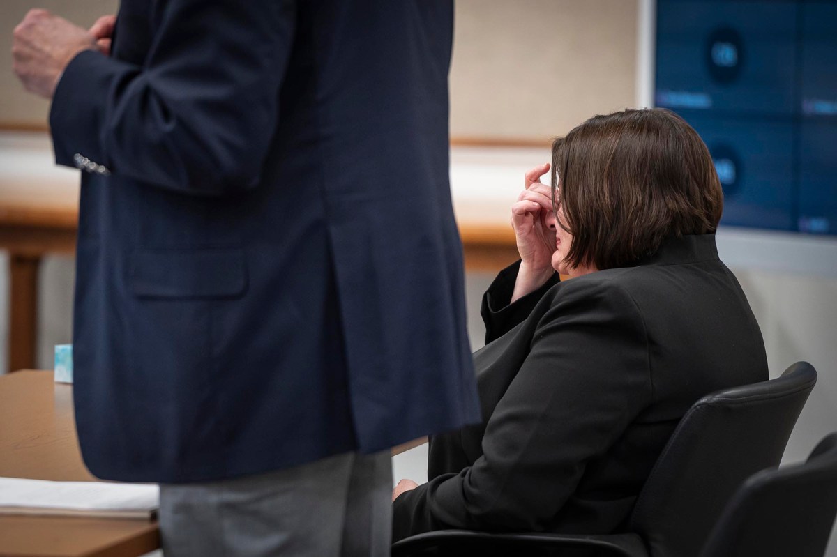 A woman in a suit sits in a courtroom.