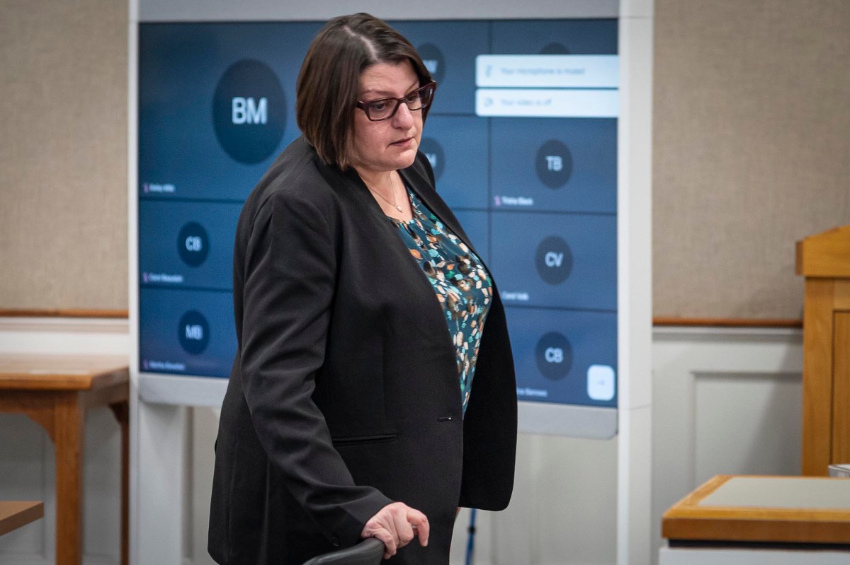 A woman in a suit walking through a courtroom.