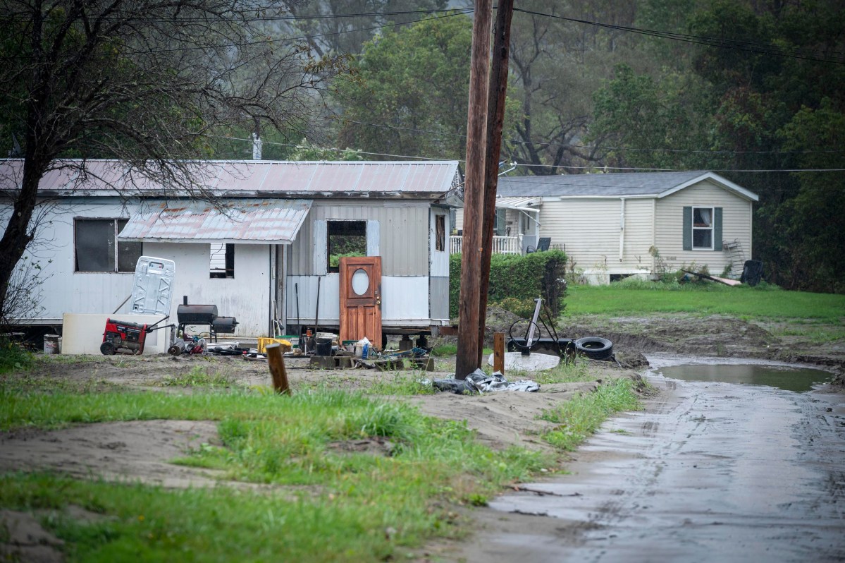 A mobile home sits on the side of a muddy road.