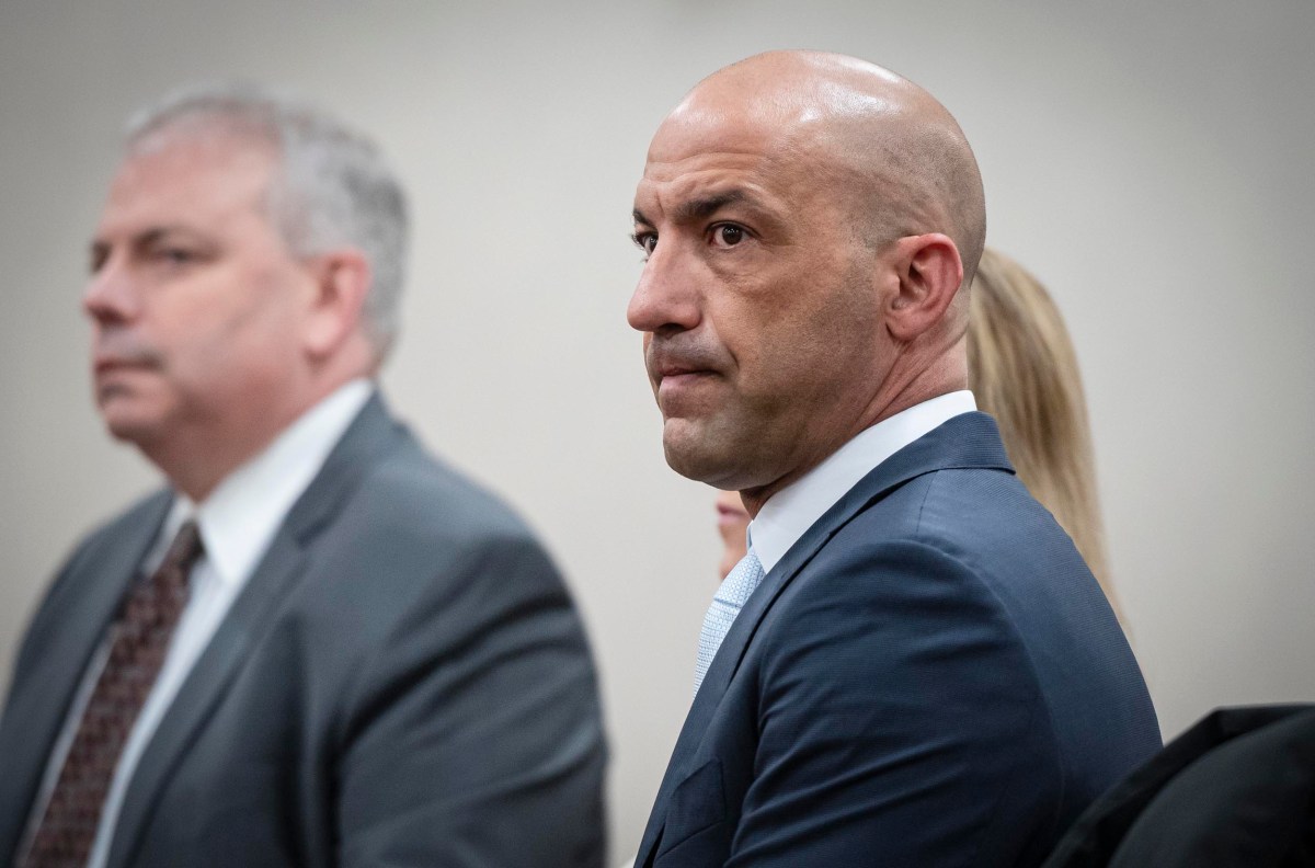 Two men in business attire, one with a focus on a bald individual with a serious expression.