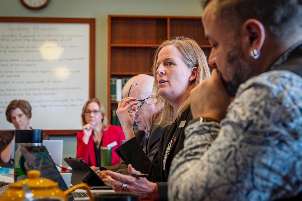 A group of people sitting around a table with laptops.