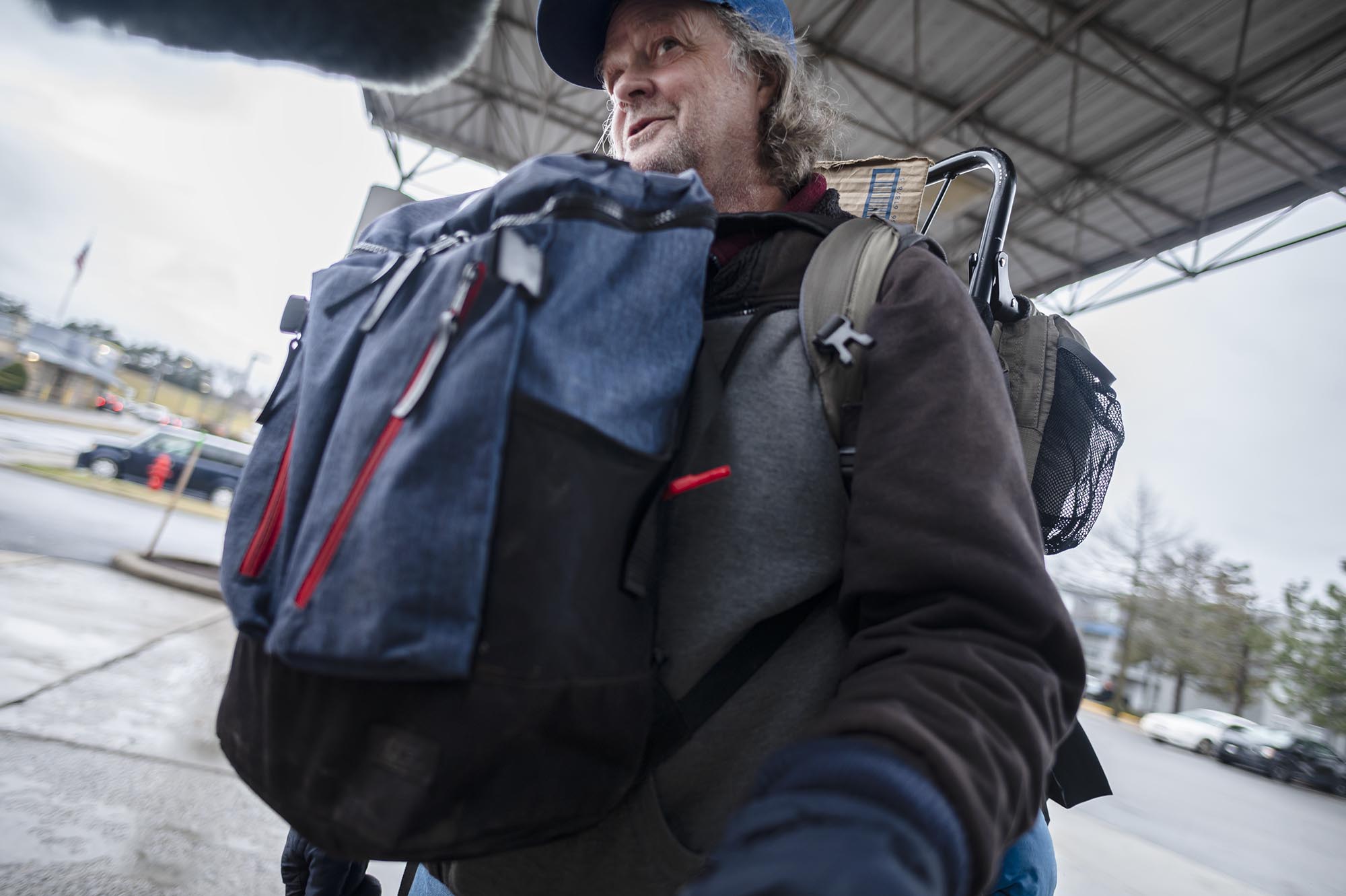 A man carrying a large backpack viewed from a low angle.
