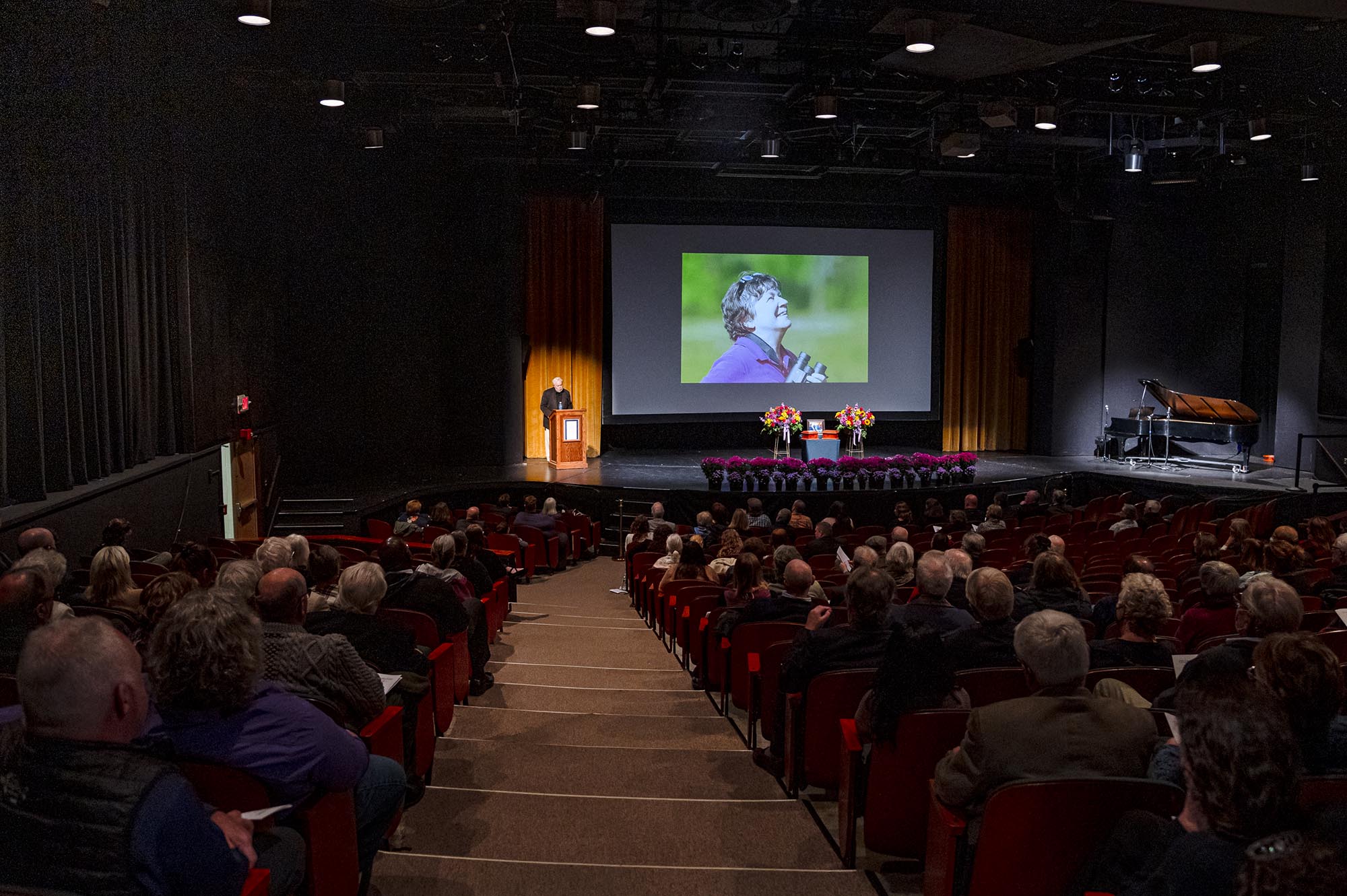 A large auditorium filled with people watching a movie on a screen.