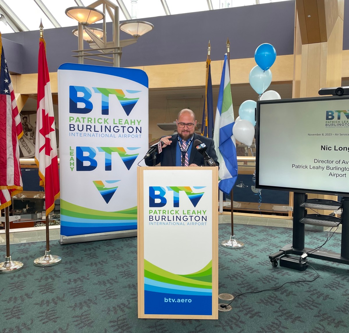 A man standing at a podium in front of flags.