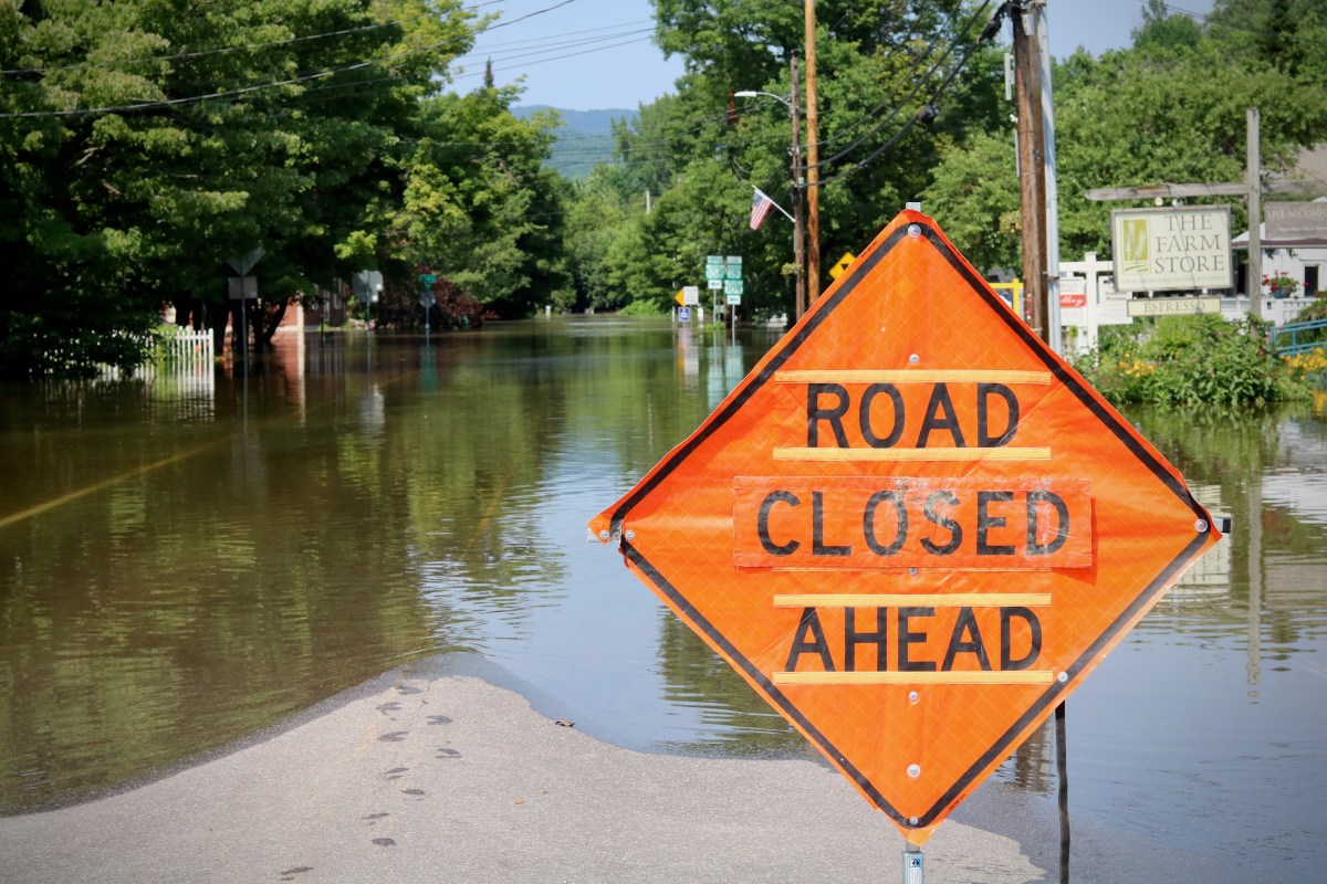 A road closed ahead sign in the middle of a flooded street.