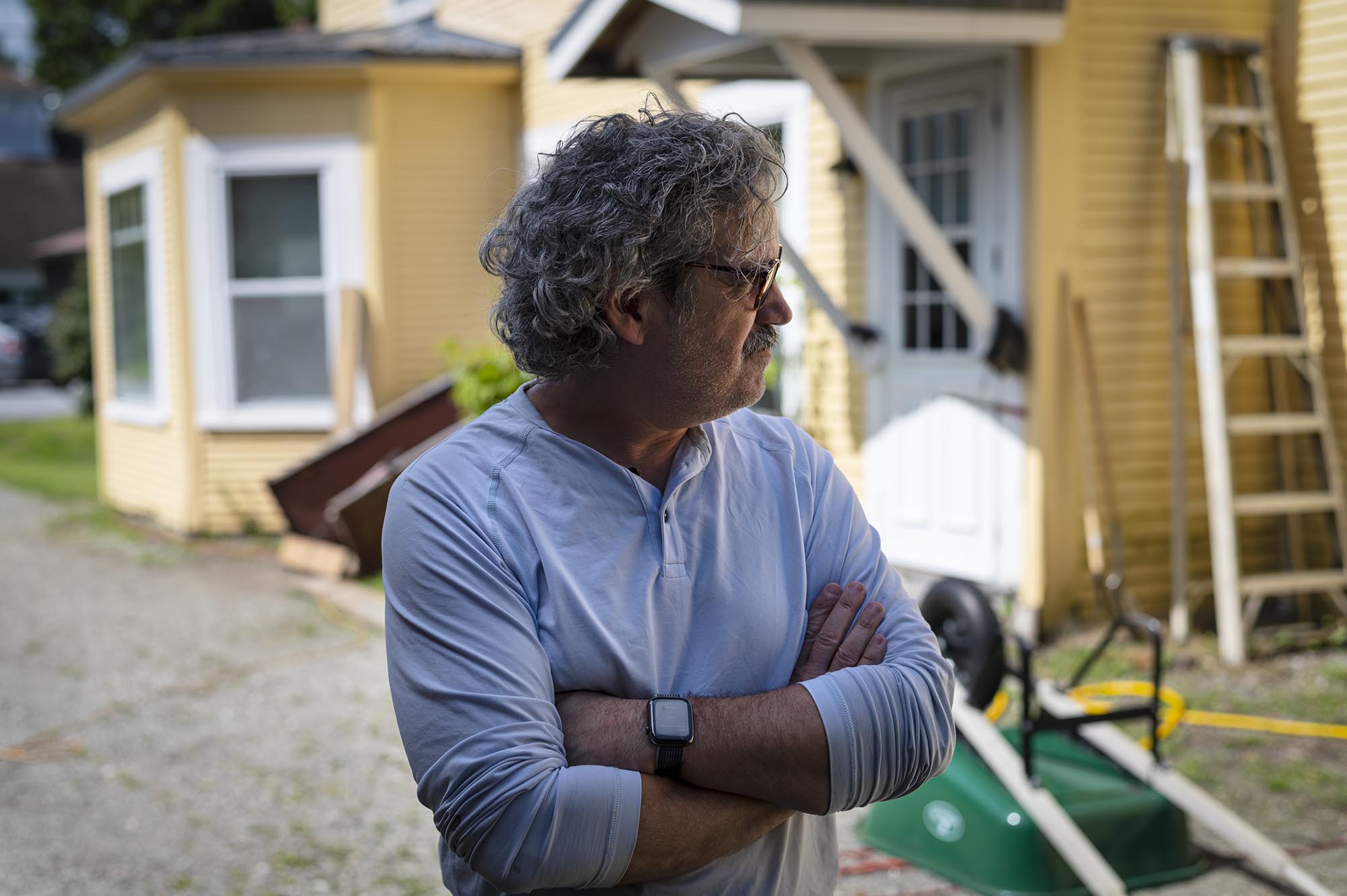A man standing in front of a yellow house.