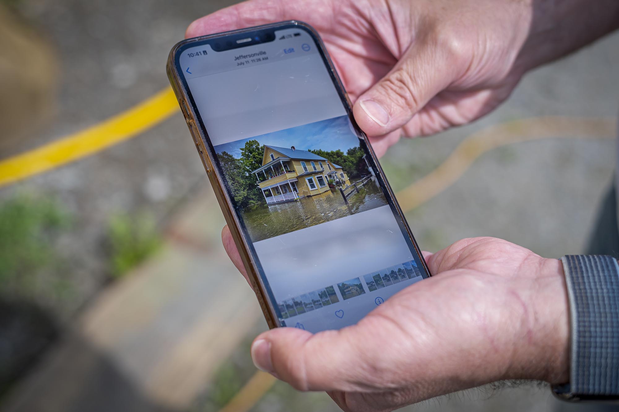 A man is holding up a phone with a picture of a house.