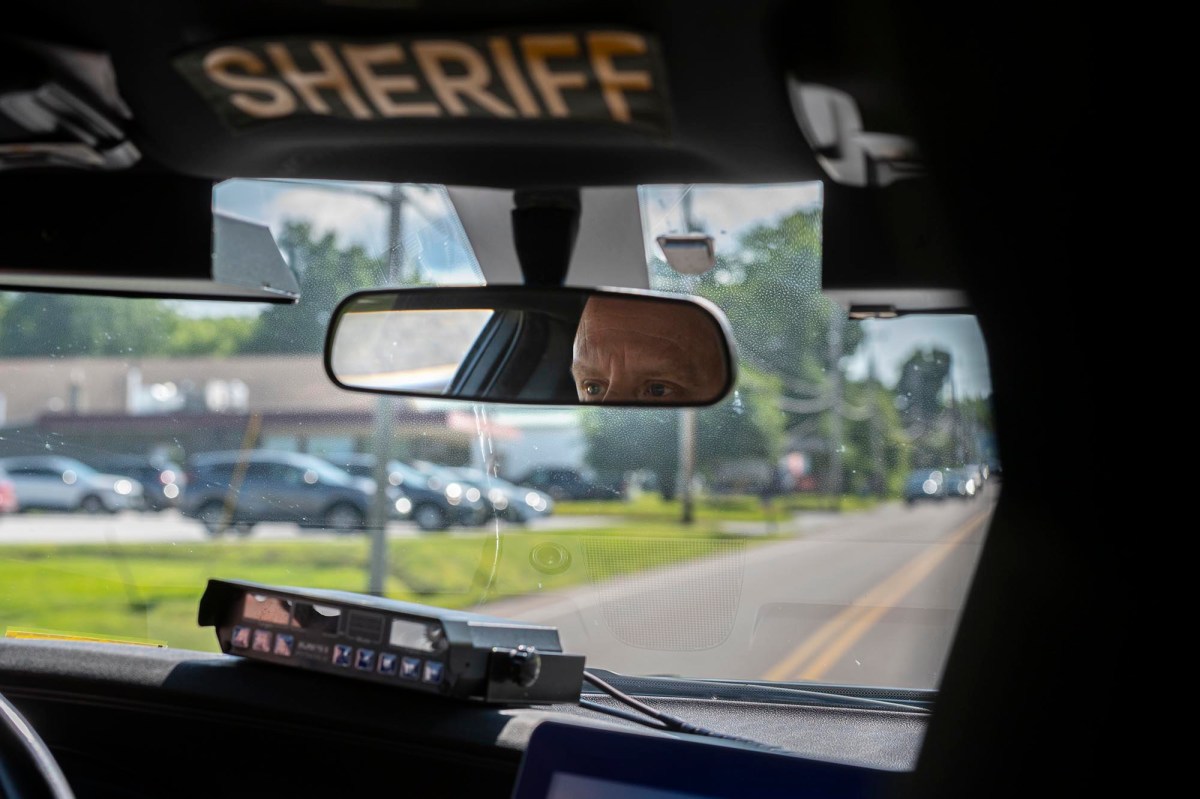 A sheriff's car with a man in the driver's seat.