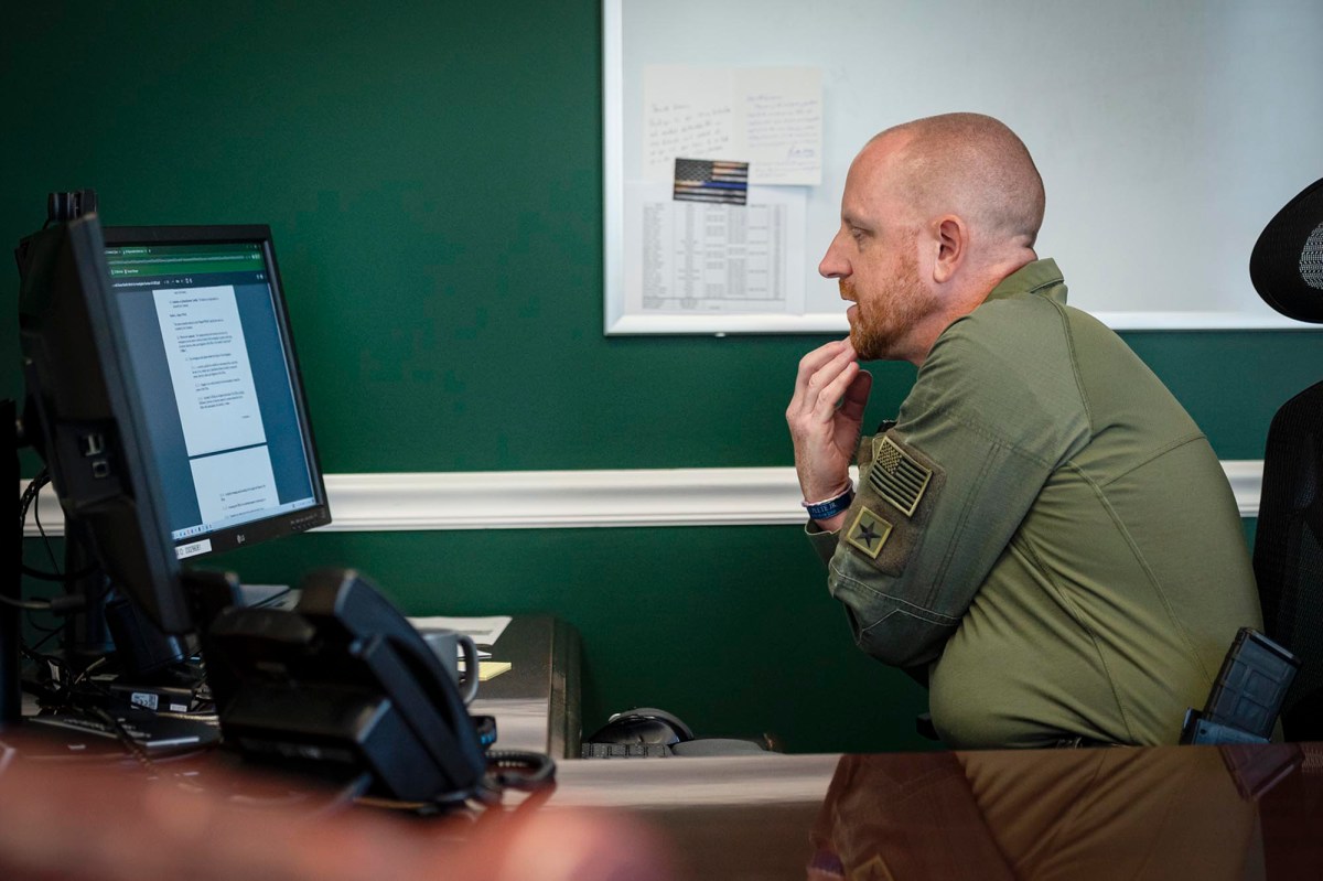 A man sitting at a desk looking at a computer.