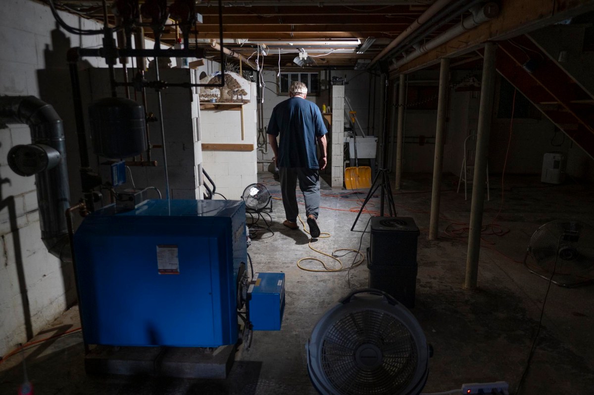 A man standing in a basement with an air conditioner.