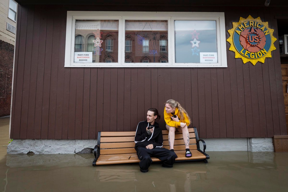 two people sitting on a bench in a flooded building.