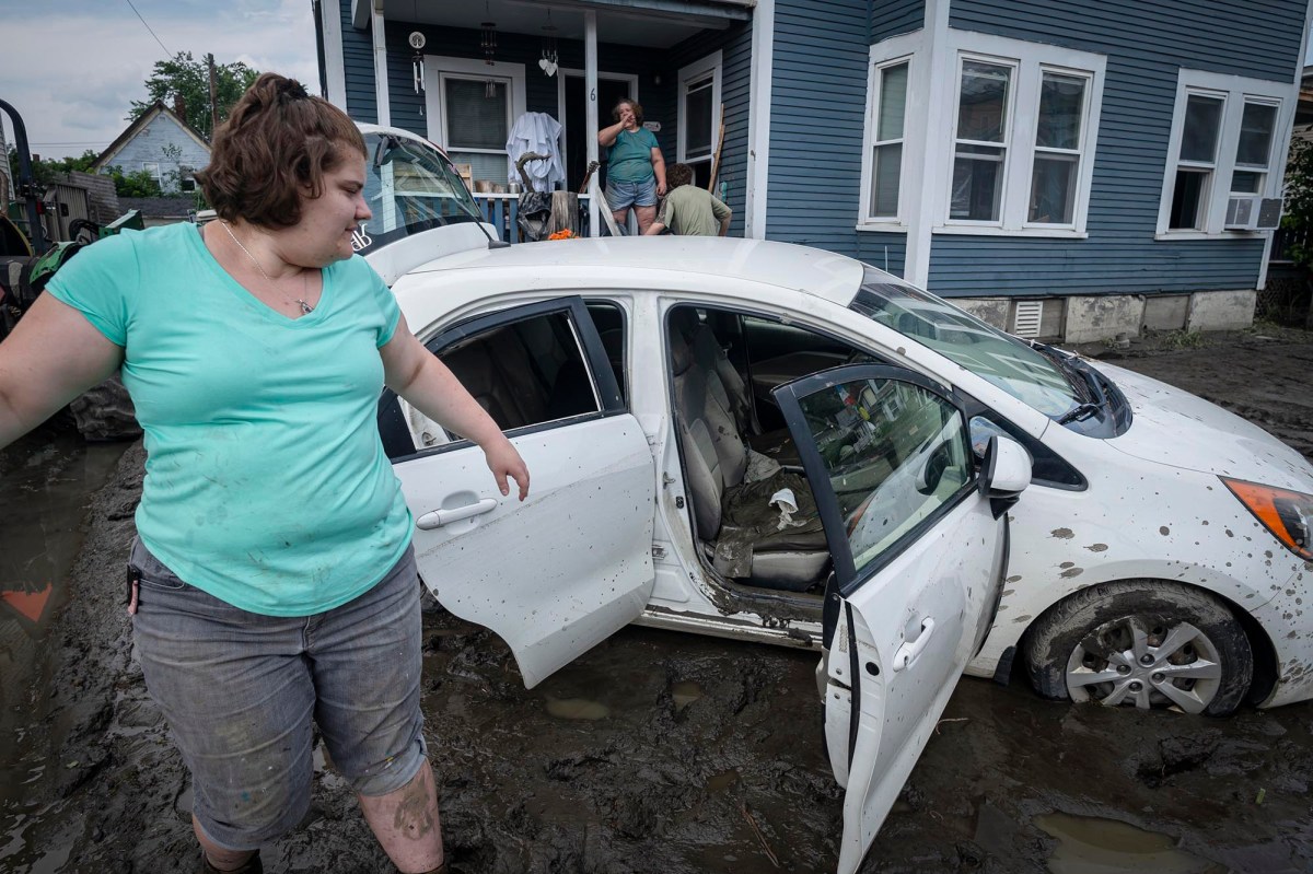 a woman standing next to a flooded car.