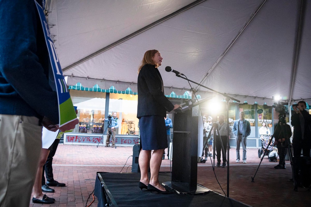 A woman standing at a podium in front of a crowd.