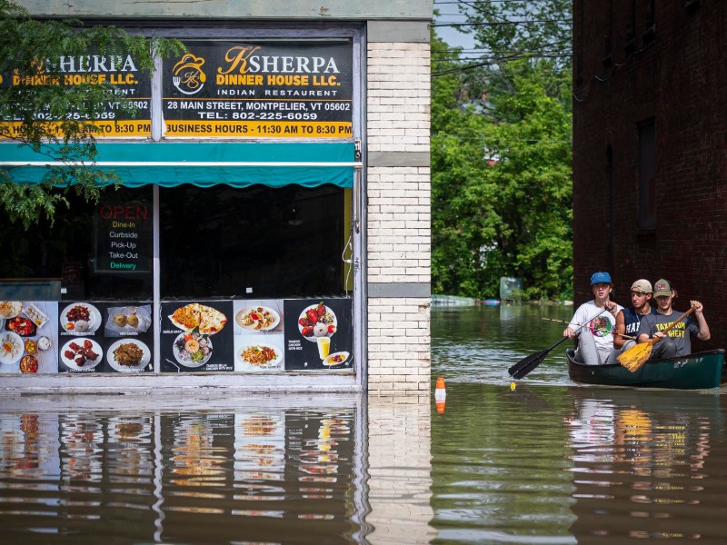 A group of people in a canoe on a flooded street.