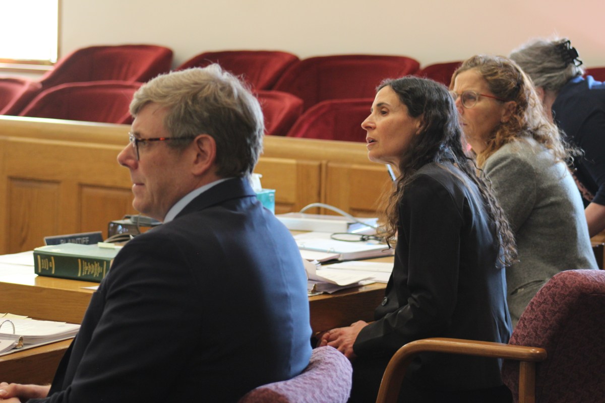 Individuals seated in a courtroom, attentively looking forward.