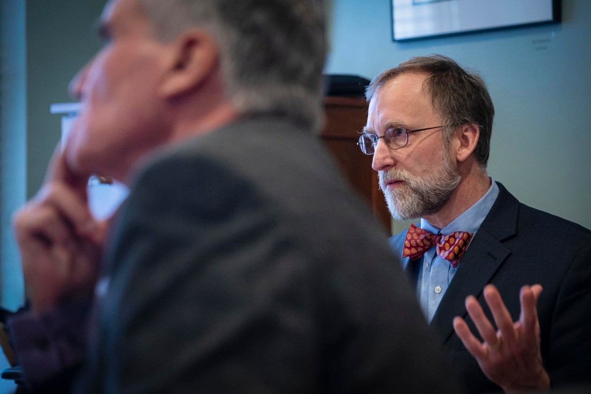 A man in a suit and bow tie is talking to another man.