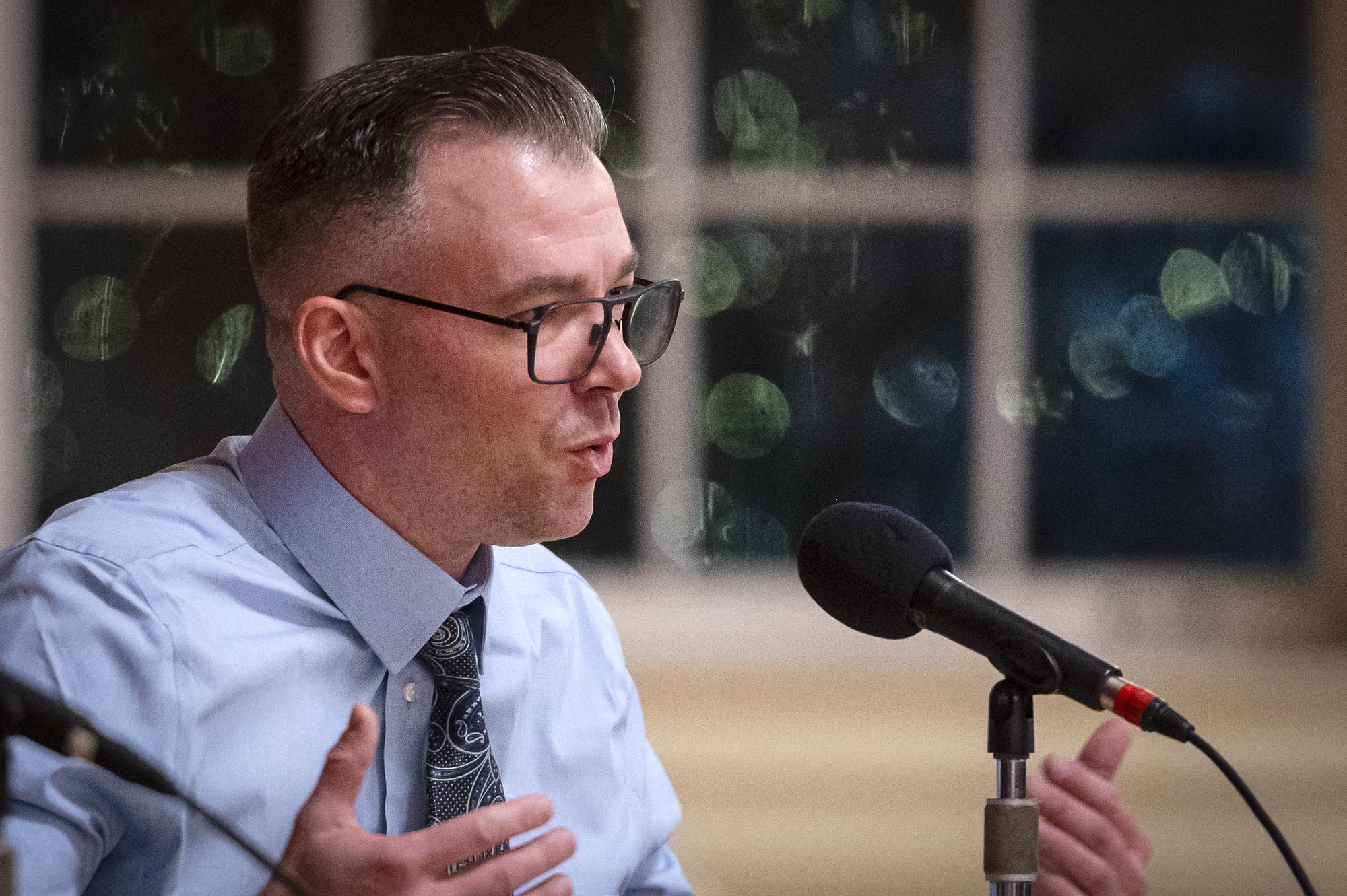 A man in glasses is speaking into a microphone.