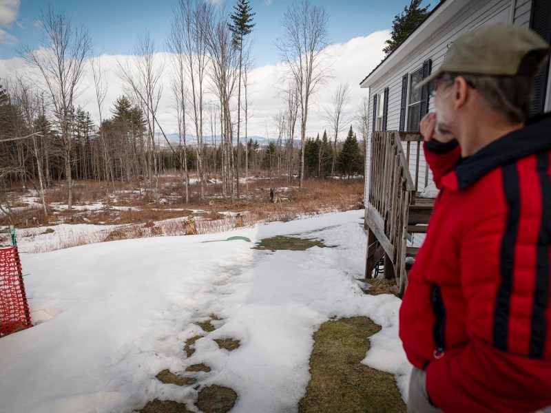 A man in a red jacket looking at some land.