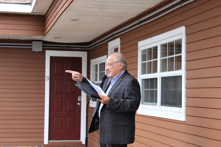 A man in a suit standing outside of a house.